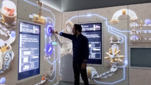 A person interacts with a digital escape room experience, featuring projected visuals and touchscreen interfaces, developed for BMW’s research and technology department in Munich.
