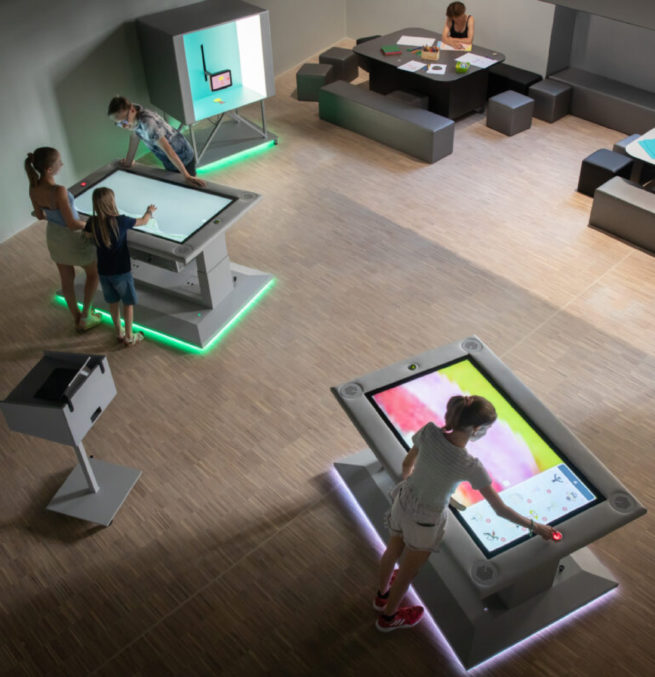 Children interacting with large touchscreen animation tables in a learning space at Zoom Kindermuseum in Vienna.